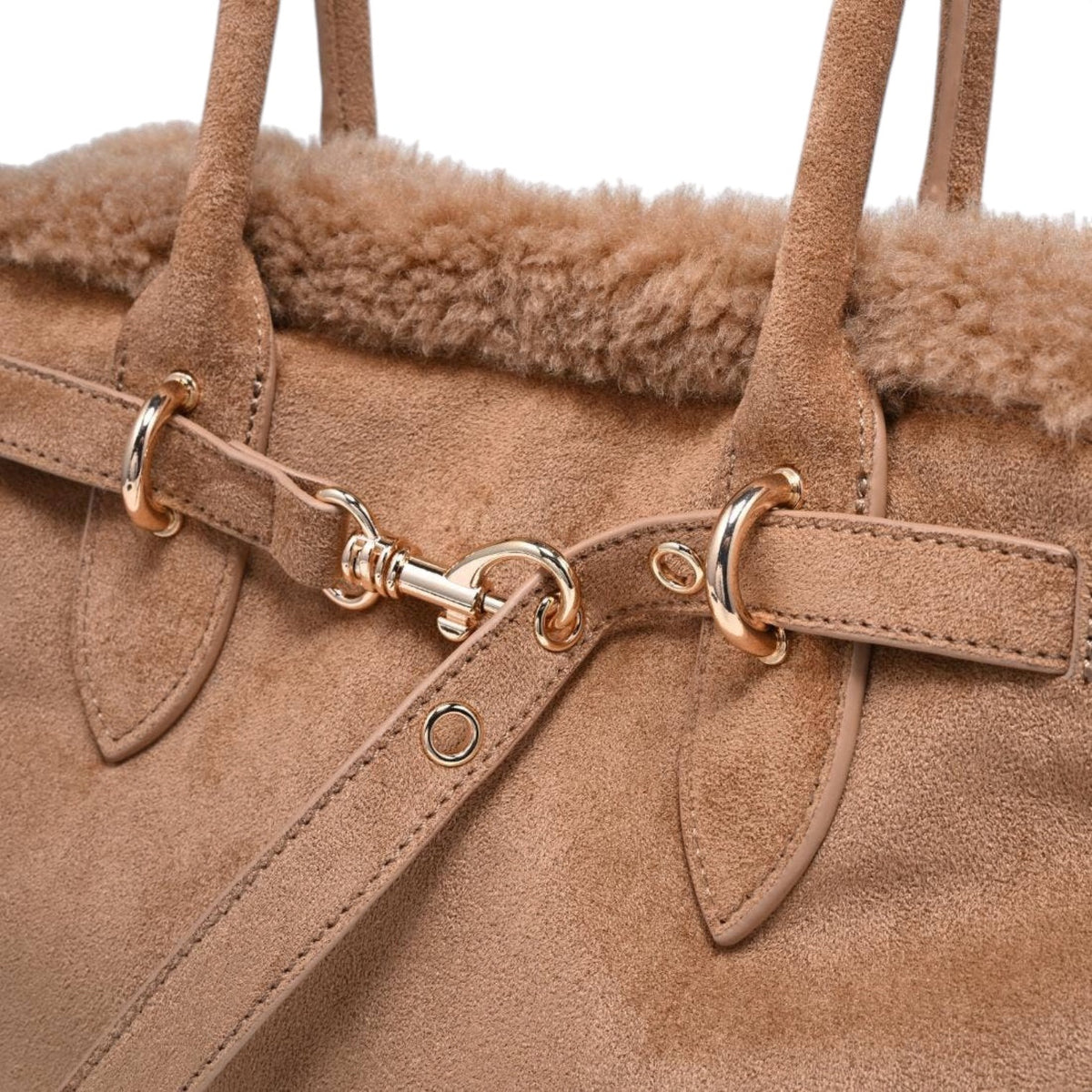 Close-up of a brown suede handbag with gold hardware on a white background