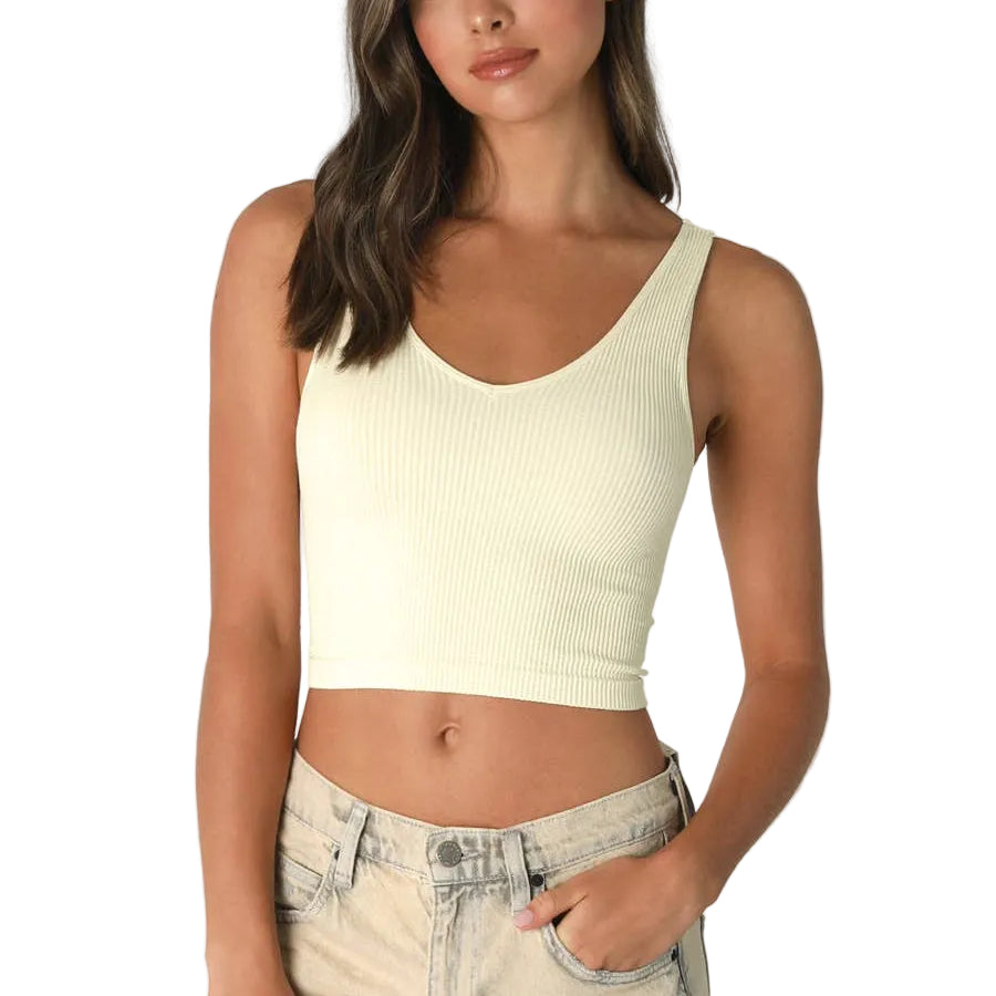 Woman wearing a light yellow ribbed tank top on a white background