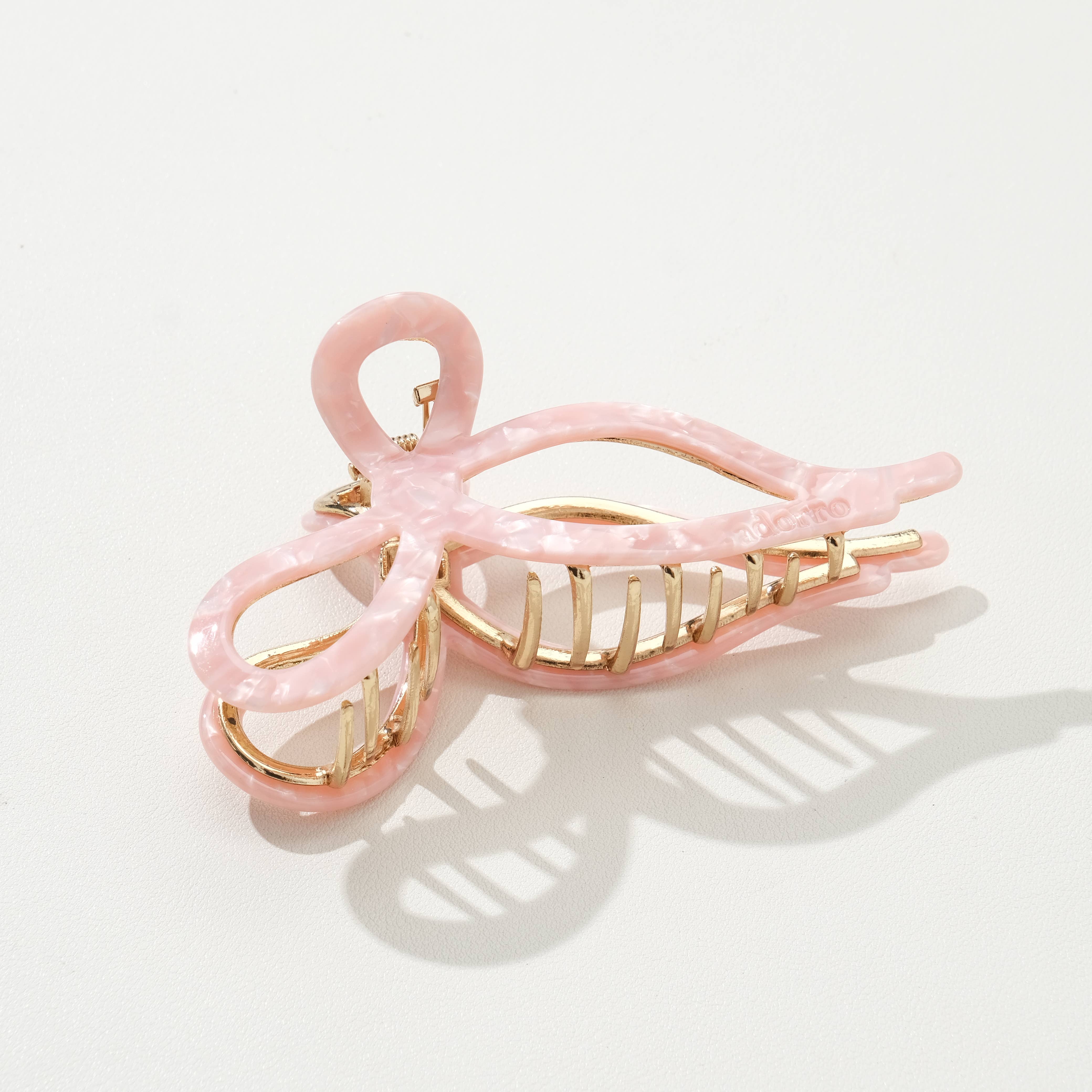 Pink hair clip with gold accents on a white background