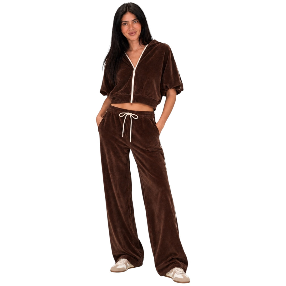 A woman modeling a brown velvet lounge set consisting of a cropped zip-up top with short puff sleeves and matching wide-leg drawstring pants, shown against a plain white background.