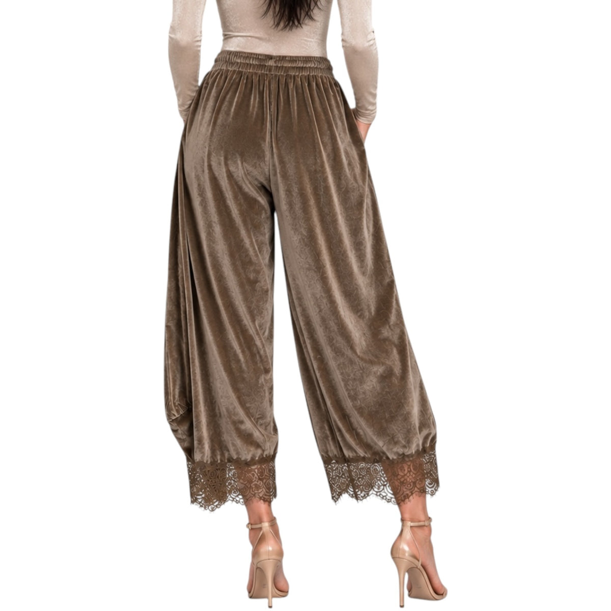 A model shown from the back wearing wide-leg brown velvet pants with a lace hem, paired with a beige long-sleeve top and nude high heels, against a plain white background.