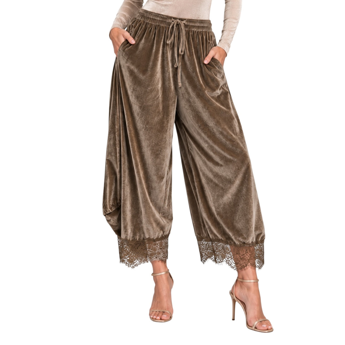 A model wears wide-leg harem-style pants in a brown velvet fabric with a drawstring waist, side pockets, and lace trim at the hems, paired with a beige long-sleeve top and heeled sandals against a white background.