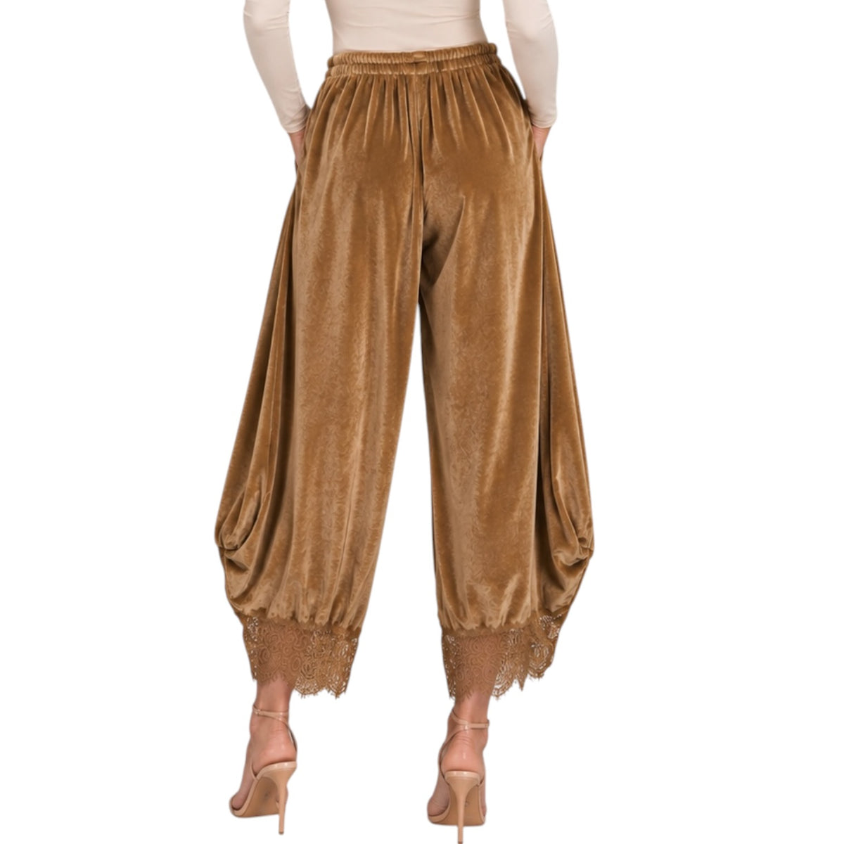 A person wearing loose, balloon-style pants in a rich camel brown velvet fabric with a lace-trimmed hem, paired with a cream long-sleeve top and nude high-heeled sandals, shown against a plain white background.