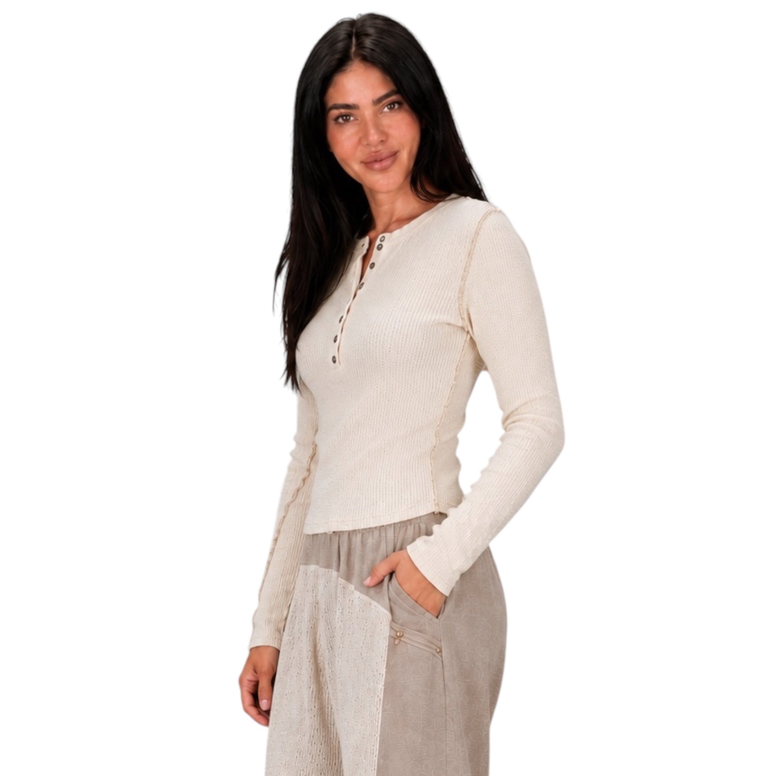 A woman modeling a ribbed long-sleeve henley top in cream, paired with light beige trousers, against a solid white background.