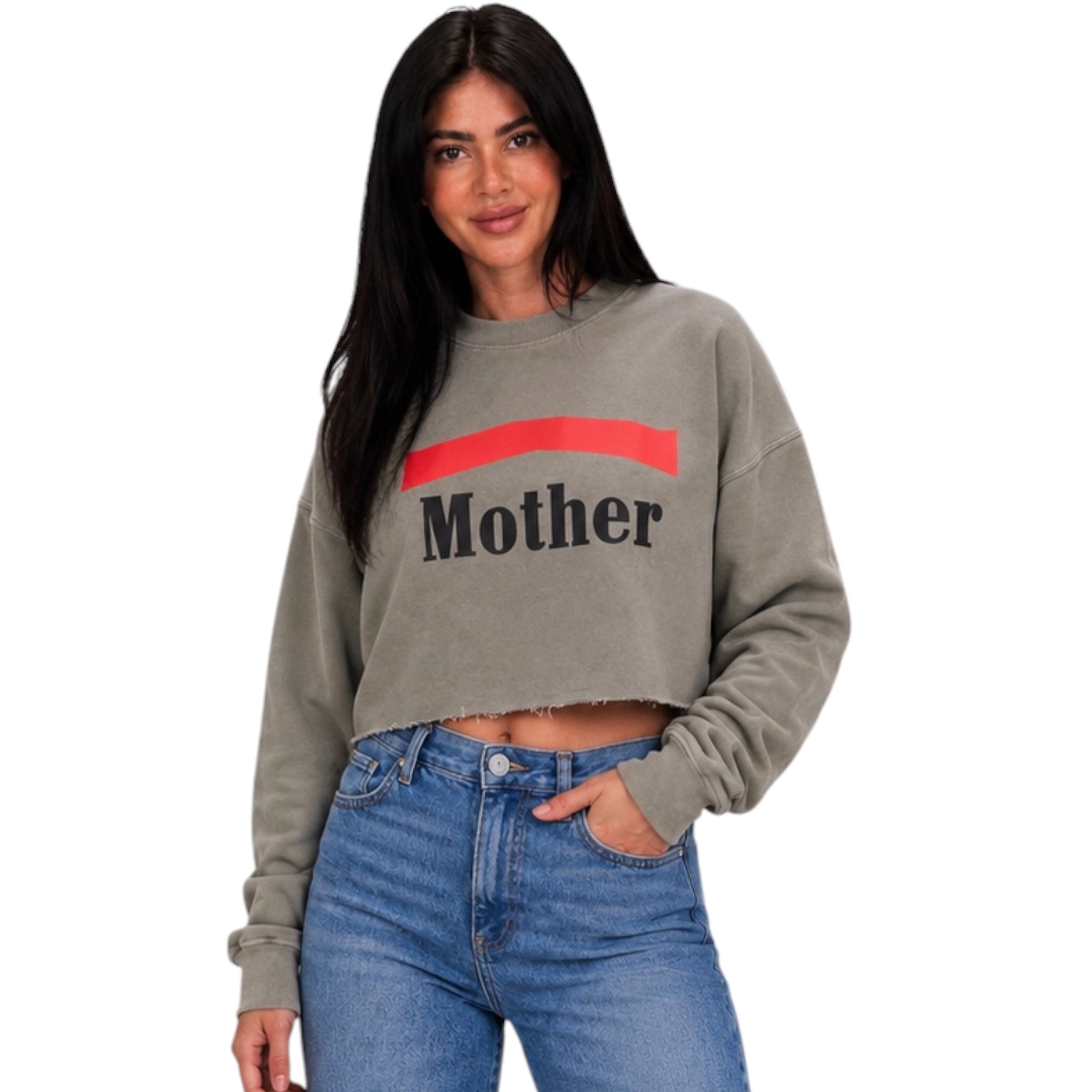 A woman modeling a cropped, faded gray sweatshirt with a red graphic stripe and the word 'Mother' printed in black across the chest, paired with blue jeans against a plain white background.