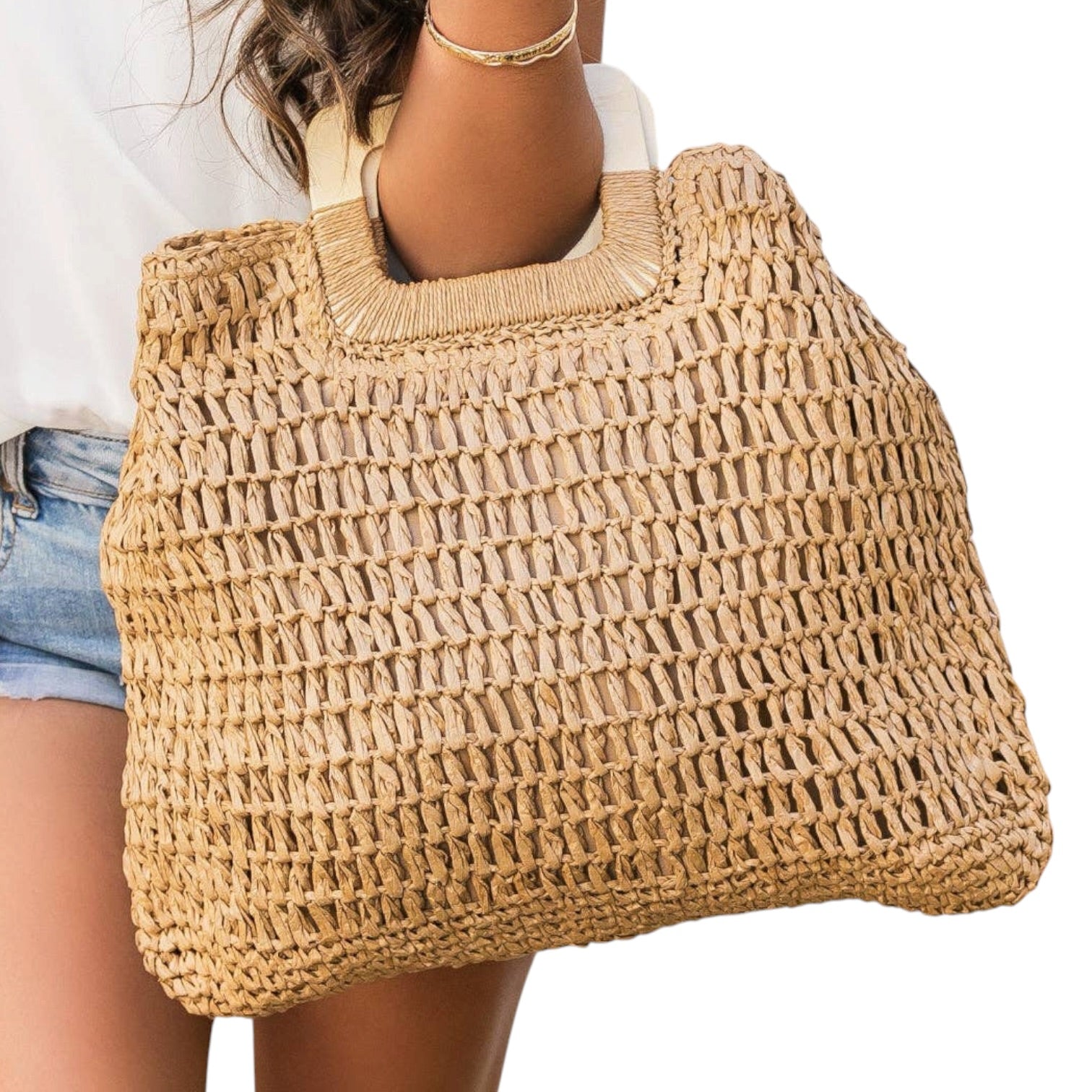 Woven straw bag held by a person on a white background