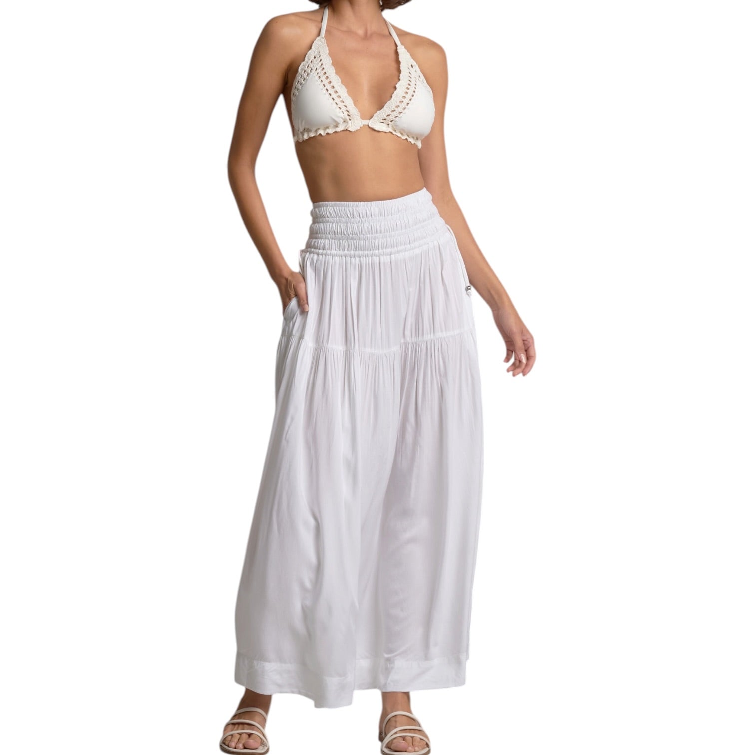 Woman wearing a white bikini set with a long white skirt on a white background