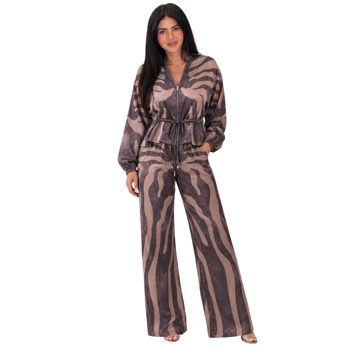A woman modeling a matching two-piece jumpsuit set with a brown and beige zebra-like animal print. The set includes a long-sleeve zip-up top with a drawstring waist and matching wide-leg pants, shown against a plain white background.