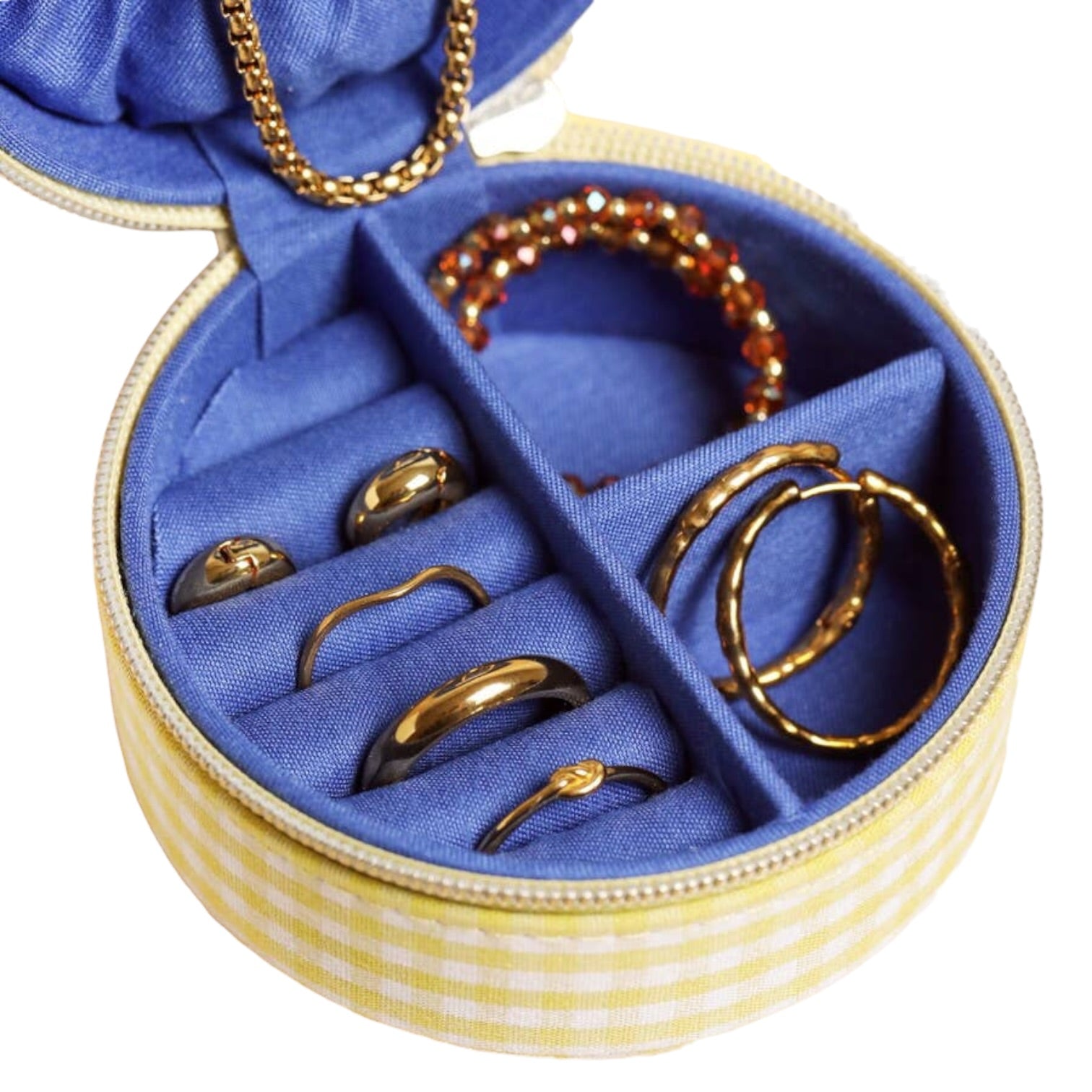 Round jewelry box with gold rings and a beaded bracelet on a white background