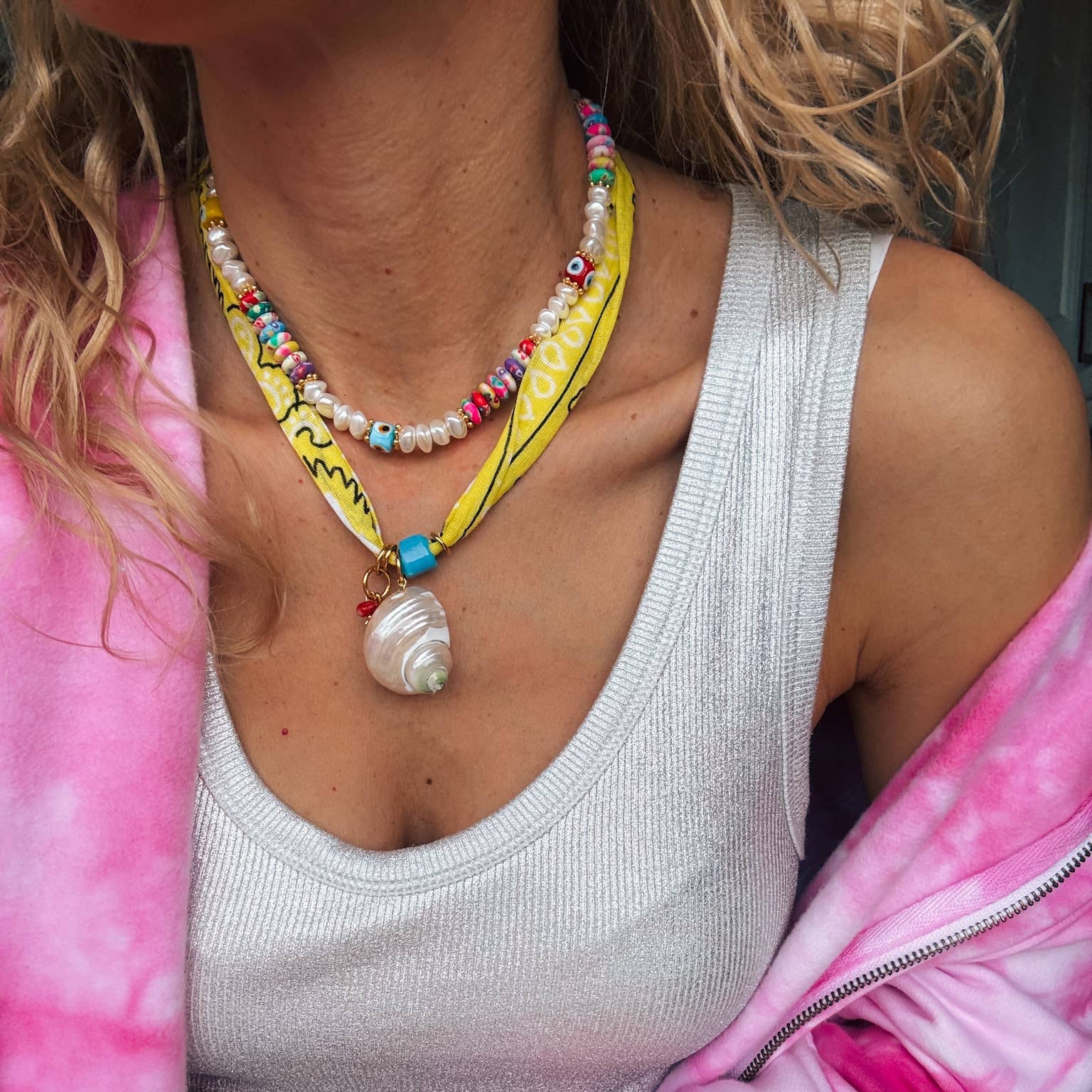 Vibrant yellow bandana necklace with shell charm and multicolor beaded pearl necklace worn with casual attire.