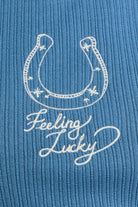 Embroidery detail of a horseshoe and 'Feeling Lucky' text on a dusty blue rib tank top.