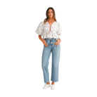 Woman wearing a pink ditzy floral bow crop top with puff sleeves, paired with high-waisted jeans and sneakers.
