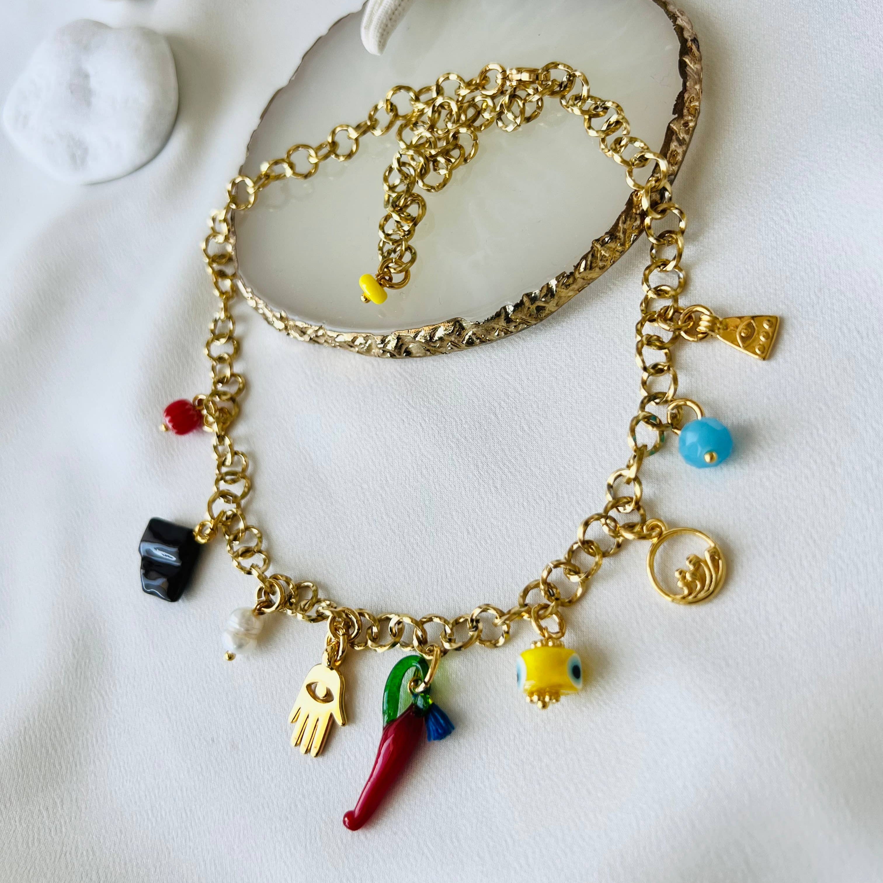 Gold charm summer necklace featuring colorful beads and playful charms on a delicate chain against a soft background.