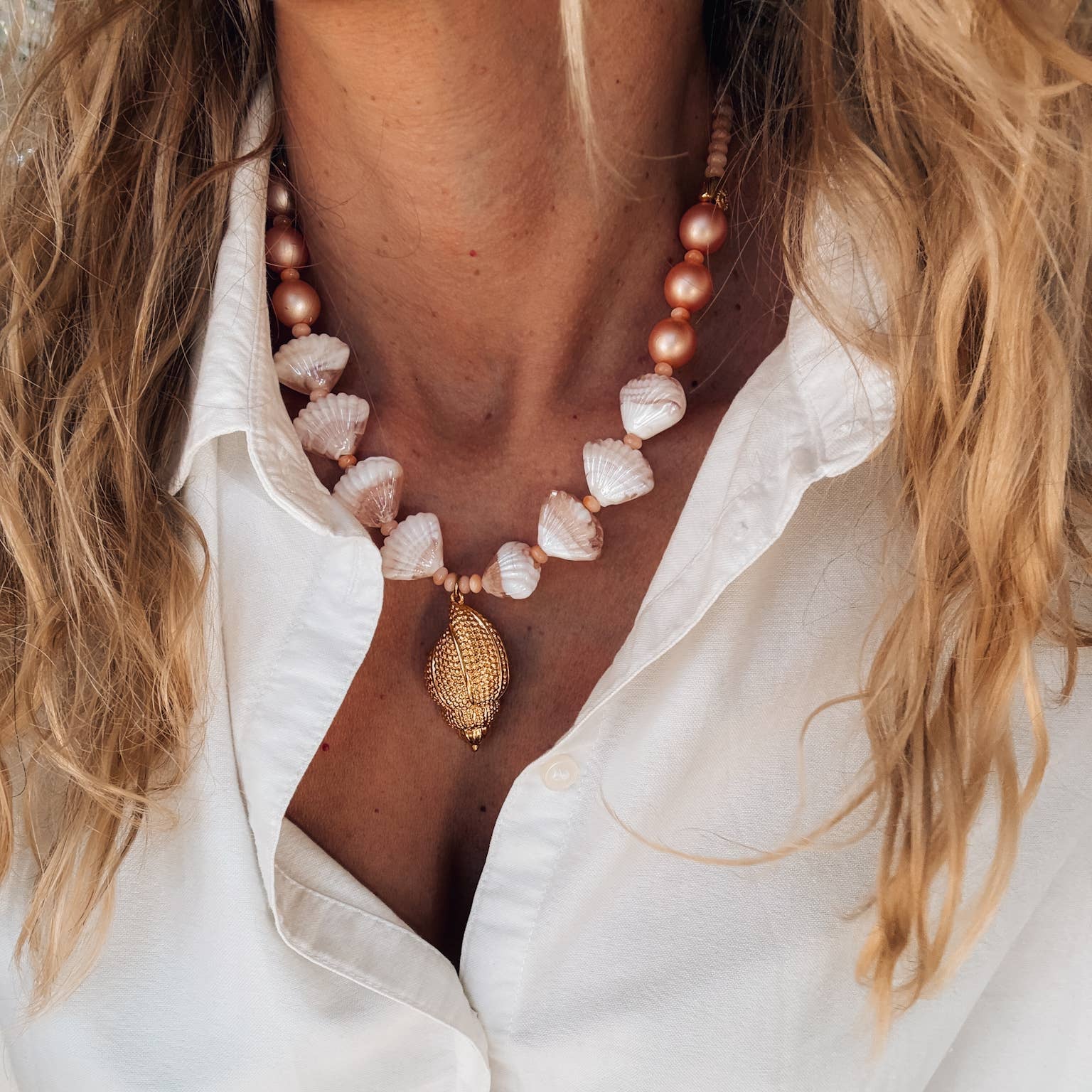 Gold large shell statement necklace in salmon pink, perfect for summer beach outfits, featuring acrylic beads and scallop shells.