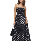 Woman wearing a black strapless dress with white polka dots on a white background