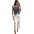 Woman wearing a denim top and white pants taking a mirror selfie.