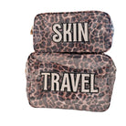 Leopard print toiletry bags with 'SKIN' and 'TRAVEL' text on a white surface.