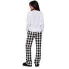 A woman shown from the back wearing a white long-sleeve top and black-and-white buffalo plaid pajama pants, standing against a plain white background.
