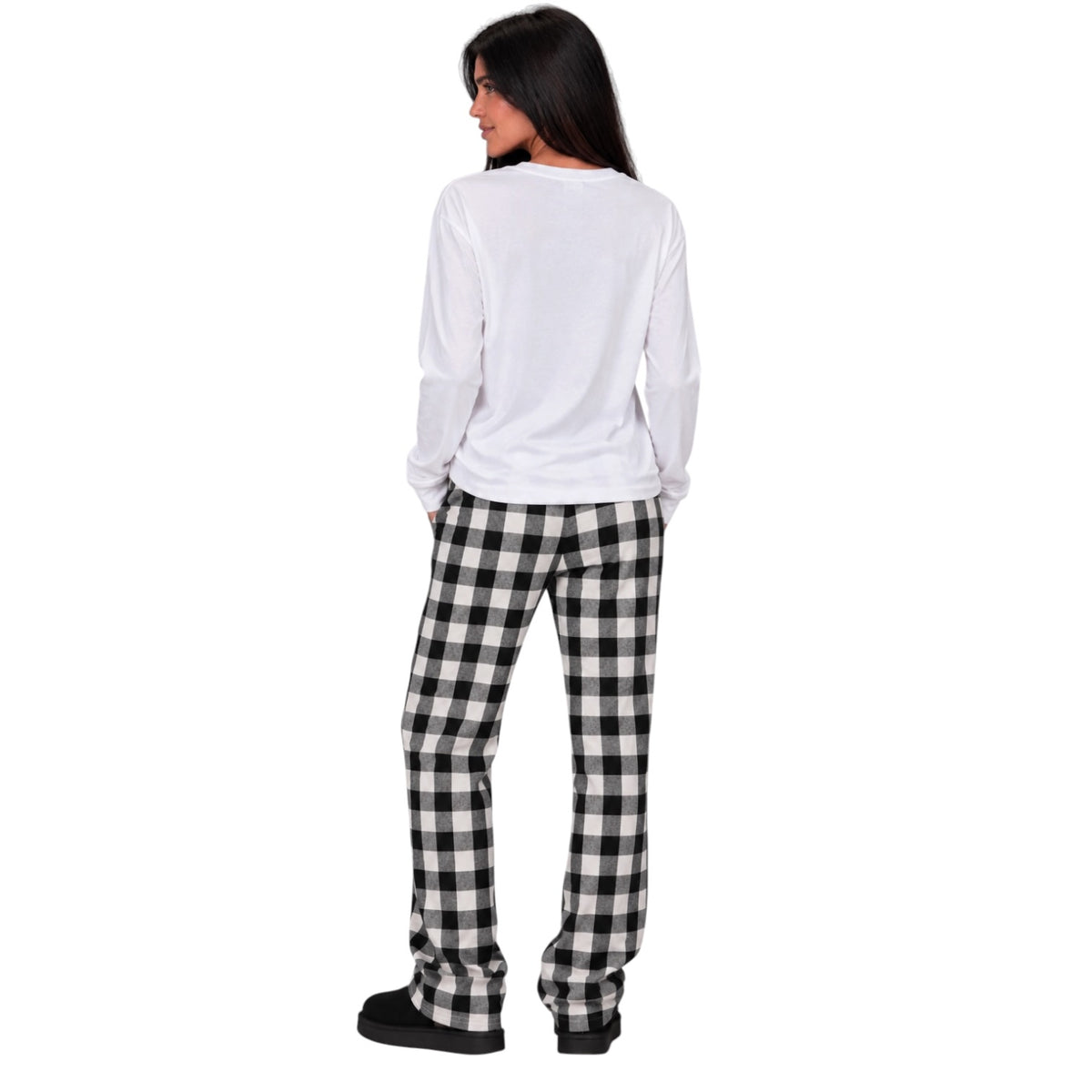 A woman shown from the back wearing a white long-sleeve top and black-and-white buffalo plaid pajama pants, standing against a plain white background.