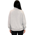 A person shown from the back wearing a light heather gray sweatshirt and black pants against a plain white background.