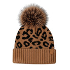 A brown knit beanie with a black leopard print pattern and a large brown faux fur pom-pom on top, shown against a plain white background.