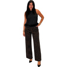 A woman modeling a sleeveless black top with a fuzzy black hem and wide-leg brown leopard-print pants, standing against a plain white background.