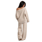 A woman shown from the back wearing a matching fuzzy knit loungewear set in a light beige color, consisting of an off-the-shoulder sweater and wide-leg pants, against a plain white background.