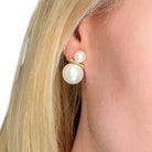 Pearl earring worn by a person with blonde hair on a white background