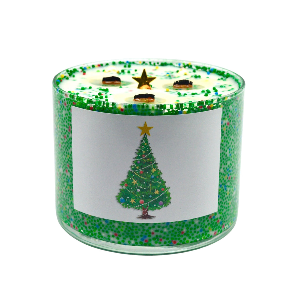 A three-wick scented candle in a clear glass jar with a green glittery exterior and a white front label featuring a green Christmas tree illustration. The lid is decorated with green sprinkles and a gold star, with three dark wicks visible.
