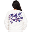 A person viewed from the back wearing a white sweatshirt with a large purple and blue script graphic reading 'Family over Everything' across the back.