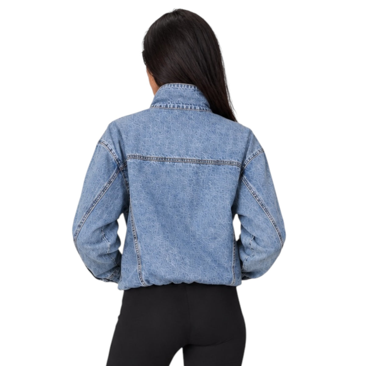 A woman viewed from the back wearing a cropped light blue denim jacket and black pants against a plain white background.