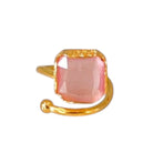 Gold ring with a pink square stone on a white background