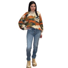 Woman wearing a colorful sweater and blue jeans on a white background