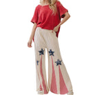 Woman wearing a red top and beige pants with star designs on a white background