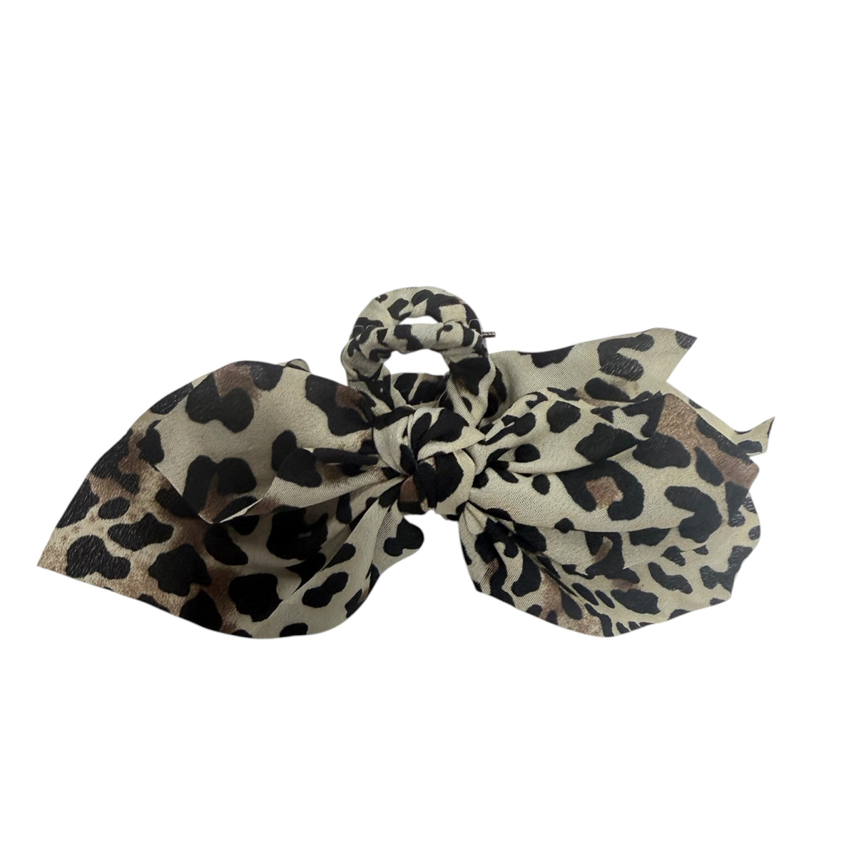 A leopard print hair bow accessory featuring a beige background with black and brown spots, photographed on a solid white background.