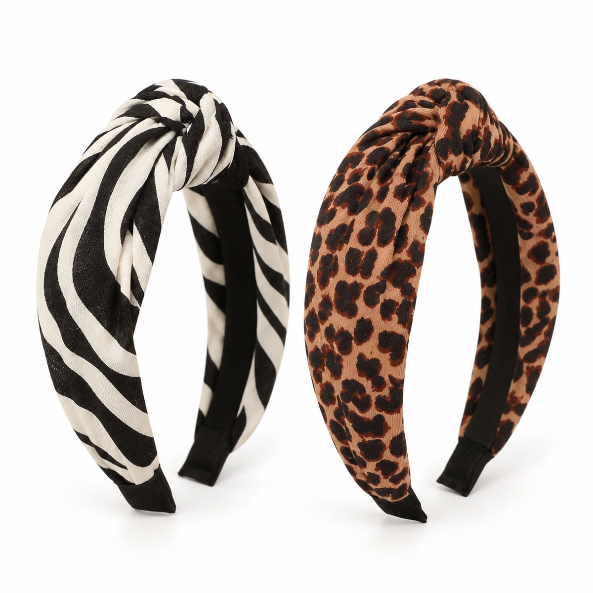 Two wide fabric headbands with twisted tops on a plain white background. The left headband has a black and off-white zebra stripe pattern, and the right headband has a brown, black, and tan leopard print pattern.
