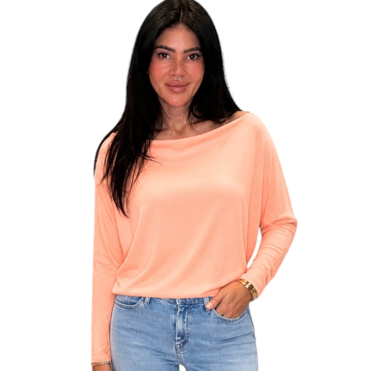 Woman wearing a peach long-sleeve top and blue jeans on a white background