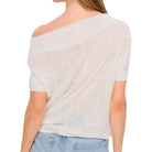 Woman wearing a light-colored, short-sleeve top and blue jeans on a white background