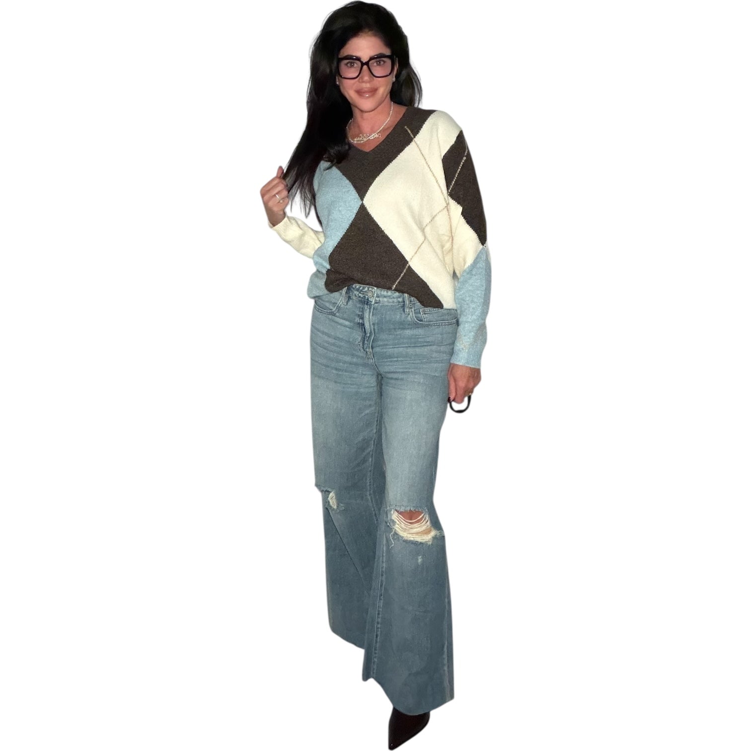 Person wearing a patterned sweater and distressed jeans on a white background