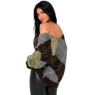 A woman modeling an off-the-shoulder knit sweater with an argyle pattern in brown, gray, and olive green, paired with black pants against a plain white background.