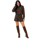 A woman modeling a matching knit sweater and shorts set with an argyle pattern in brown, dark gray, and beige, paired with brown suede knee-high boots, against a plain white background.
