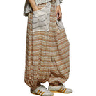 Person wearing a patterned harem pants with a plain background