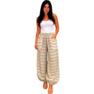 Woman wearing patterned wide-leg pants and a white top on a white background