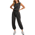 Woman wearing a dark gray sleeveless jumpsuit on a white background