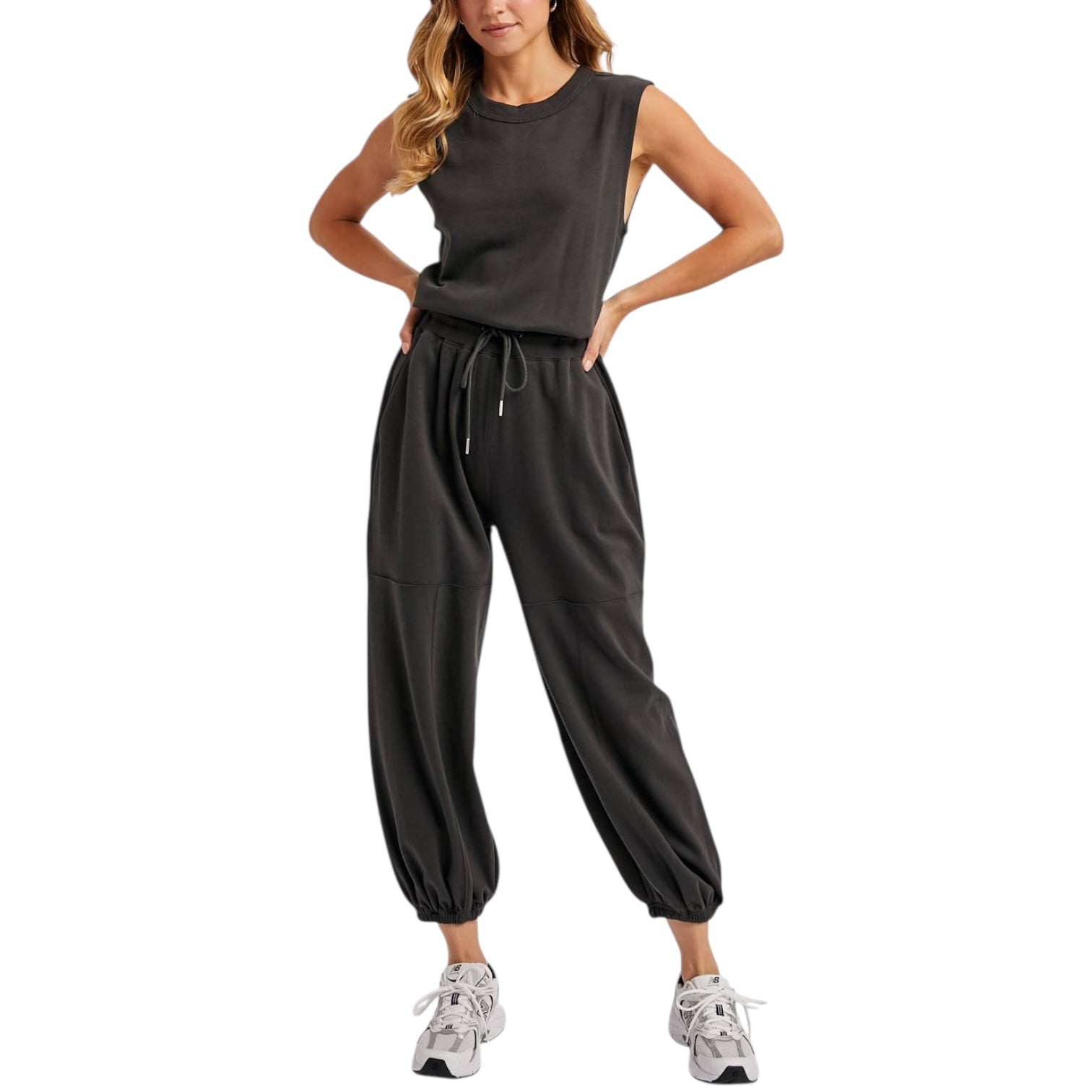 Woman wearing a dark gray sleeveless jumpsuit on a white background