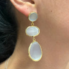 Gold and stone earring worn by a person