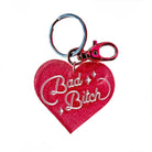 Pink glittery heart-shaped keychain with 'Bad Bitch' text on a white background