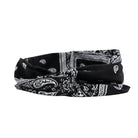 Woman wearing a black bandana with white patterns on her head, against a white background
