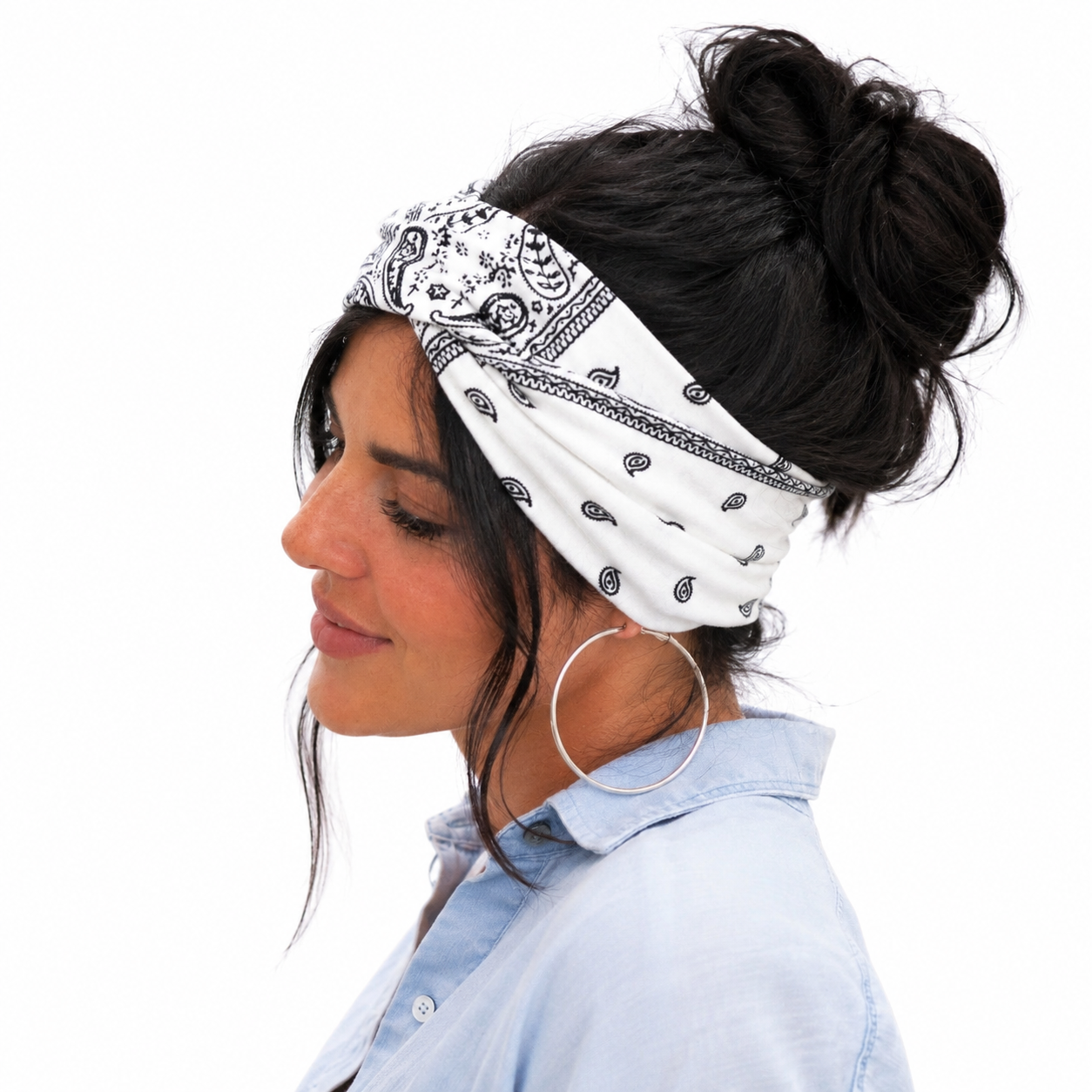 Woman wearing a white bandana with black patterns on her head, against a plain background