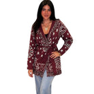 A woman modeling a long-sleeve wrap-style cardigan with a white star and paisley pattern on a burgundy base, paired with light blue jeans against a plain white background.